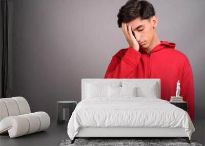 Stressed and sad Persian teenage boy against gray background Wall mural