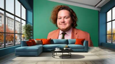 Studio Portrait of Handsome Young Man Happily Smiling Against Green Background Wall mural