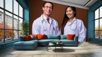 Studio shot of two young doctors together against brown backgrou Wall mural