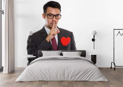 Studio shot of young Asian businessman with finger on lips and r Wall mural