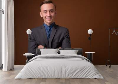 Studio shot of young handsome businessman against brown backgrou Wall mural