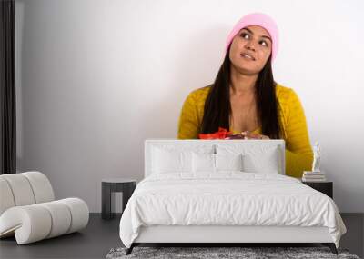 Studio shot of young happy Indian woman smiling and thinking whi Wall mural