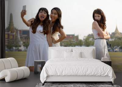 Three multi ethnic young beautiful women as friends together in the park Wall mural