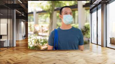 Young Asian man wearing mask for protection from corona virus outbreak with nature outdoors Wall mural