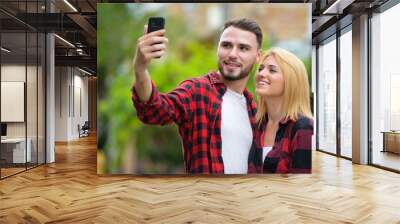 Young couple using phone together in the streets outdoors Wall mural