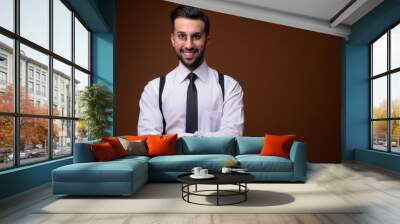 Young handsome bearded Iranian businessman against brown backgro Wall mural