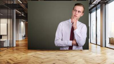 Young handsome businessman with blond hair against colored backg Wall mural