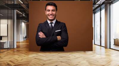 Young handsome Hispanic businessman against brown background Wall mural