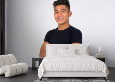 Young happy Asian man with arms crossed against white background Wall mural