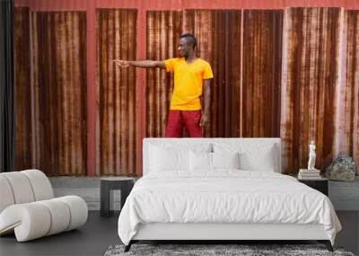 Young happy black African man smiling and pointing to the side w Wall mural