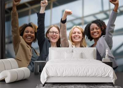 Empowered women celebrate success outside a modern building during the day, raising their fists in unity and joy Wall mural