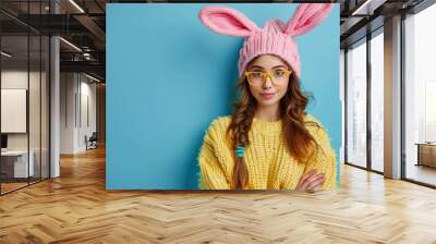 Portrait of a pretty young girl wearing bunny ears isolated over blue background Wall mural