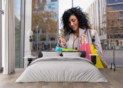 Woman shopping. Happy woman looking at shopping bags enjoying on shopping. Consumerism, shopping, lifestyle concept Wall mural