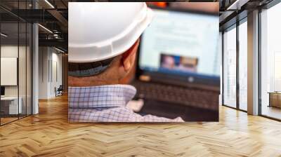 Engineer man with white helmet looking at his laptop Wall mural