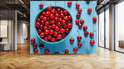 A bowl filled with fresh red cherries on a blue wooden table with scattered cherries around Wall mural