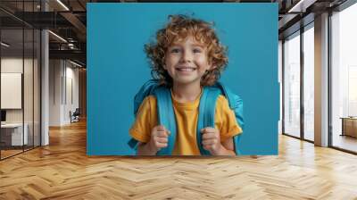 Portrait of a little boy with a backpack on a blue background Wall mural