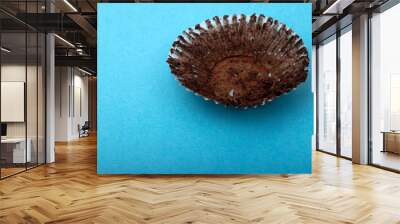 Empty chocolate muffin wrapper on a blue background Wall mural