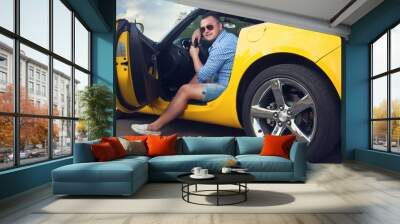 Lucky young man sitting in his new convertible car Wall mural