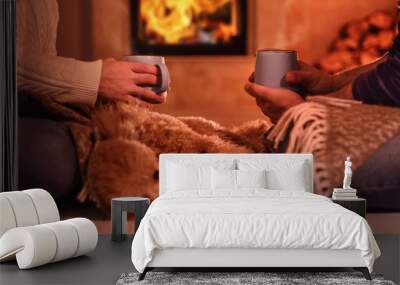 Young couple drinking cocoa on the fireplace background. Romantic concept . Wall mural