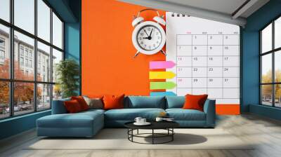 white alarm clock and opened calendar with paper tag ,  on grunge orange paper background Wall mural