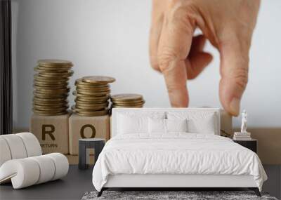 wooden cube blocks under stack of coins with letters ROI and hand turn decease to growing graph, For Return on Investment financial concept Wall mural