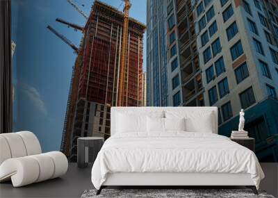 A modern construction site showcasing new high-rise buildings against a blue sky with cranes involved in the building process. Wall mural