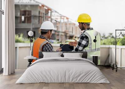 Asian people, two man, holding blueprints Structural engineers examine structural plans for office buildings and housing developments on-site, discussing work at construction site. Wall mural