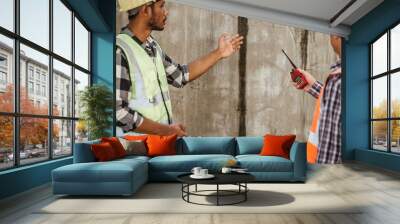 Asian people, two man, holding blueprints Structural engineers examine structural plans for office buildings and housing developments on-site, discussing work at construction site. Wall mural