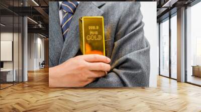 Businessman in suit sits at his desk, holding a shining gold bar. financial charts, the scene symbolizes wealth, investment success, growing influence of cryptocurrency and blockchain. Wall mural