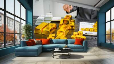 Businessman in suit sits at his desk, holding a shining gold bar. financial charts, the scene symbolizes wealth, investment success, growing influence of cryptocurrency and blockchain. Wall mural