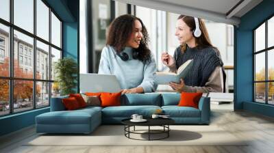 Caucasian and an African American university woman working together on a project, discussing and taking notes. Wall mural