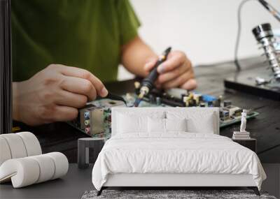 Technician carefully repairs a computer circuit board, using precision tools to address hardware issues. technical expertise needed for troubleshooting and upgrading electronic systems in workspace. Wall mural