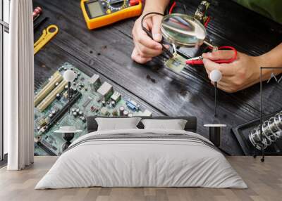 Technician carefully repairs a computer circuit board, using precision tools to address hardware issues. technical expertise needed for troubleshooting and upgrading electronic systems in workspace. Wall mural