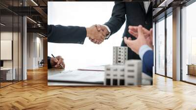 Two individuals shake hands in agreement after a successful business meeting with a condominium seller, finalizing a deal or partnership. Wall mural