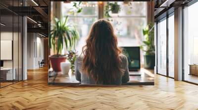 Anonymous woman sitting at her desk looking at laptop Wall mural