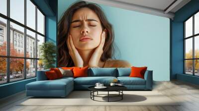 A woman expressing distress and frustration, highlighting emotions with hands on her face against a calming backdrop. Wall mural