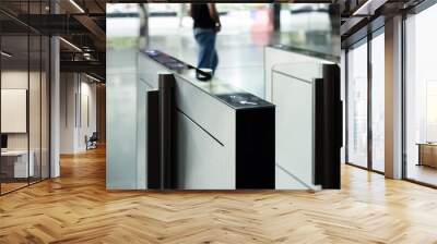 A man walks past a pair of electronic turnstiles. smart turnstiles. Wall mural