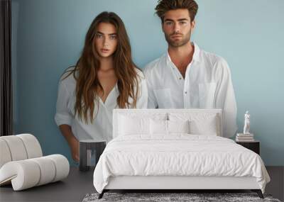 Attractive young couple posing in white shirts and denim jeans, exuding casual elegance and modern style. Wall mural