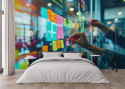 A professional's hands are arranging colorful sticky notes on a glass wall for project management and brainstorming in a modern office. Wall mural