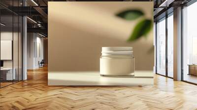 Minimalist skincare product jar on a white surface with natural light and green leaves in the background, evoking a clean and organic feel. Wall mural