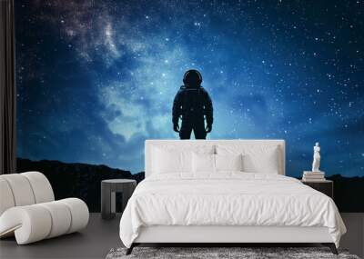 Silhouette of an astronaut standing on the edge against starry sky with Milky Way and galaxies, blue color background,  astronaut man space exploration concept Wall mural