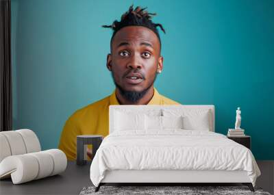 Young African American man in yellow shirt looking surprised and holding his hands Wall mural