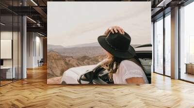 Female traveler going out of the car window to appreciate the landscape Wall mural