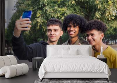 multiethnic group of three male teens smiling happy taking selfie photo with mobile phone, concept of youth lifestyle and technology of communication Wall mural