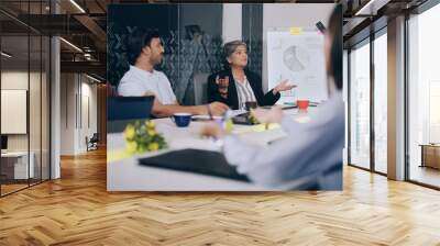 Indian Asian older aged lady boss young adult expert male female group staff sitting chair talk indoor job office. girls worker team agent man leader do project discuss new plan share idea work place Wall mural