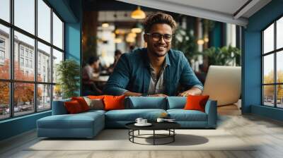 Blue color dressed smile faced man working on laptop in cafe and looking at camera Wall mural