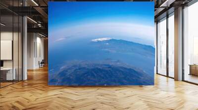 Curvature of planet earth. Aerial shot. Blue sky and clouds over island in the ocean Wall mural