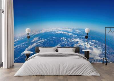 Curvature of planet earth. Aerial view. Blue sky over snowed mountain peaks. Space, science concept Wall mural