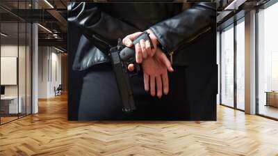 Female secret police agent, killer or spy hide a handgun. Woman hold a gun behind her back. Wall mural