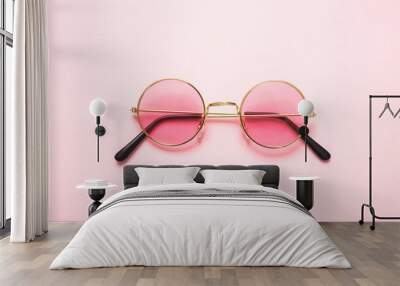 Golden frame sunglasses with pink lens on pink background, top view Wall mural